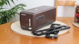 Plustek OpticFilm 35mm film scanner on a wooden table